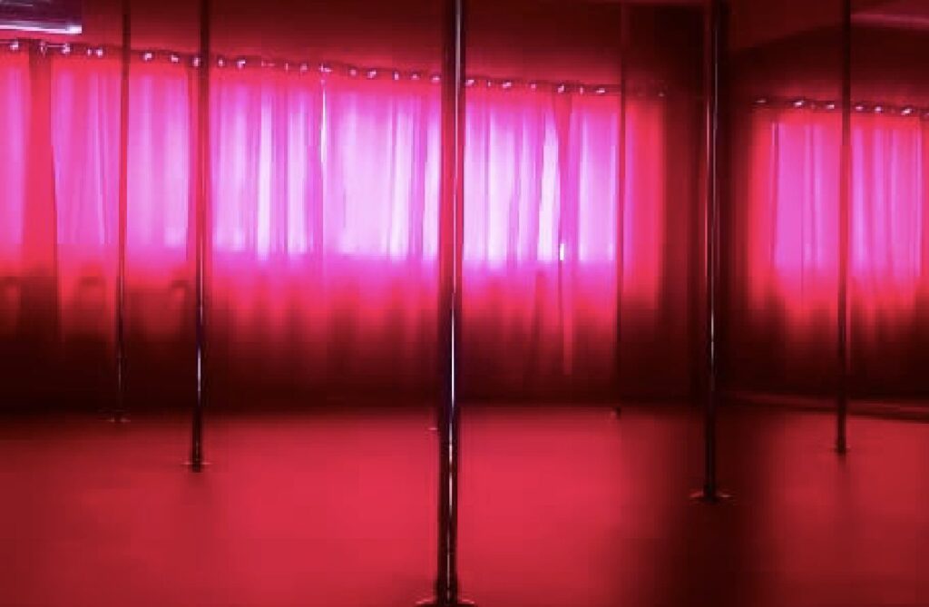 The Sinner Room: a red-lit studio with chrome poles and curtains